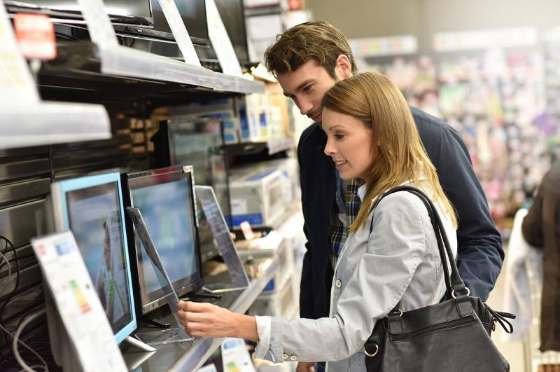 jeune femme et jeune homme consultant une pancarte tarifaire dans un magasin